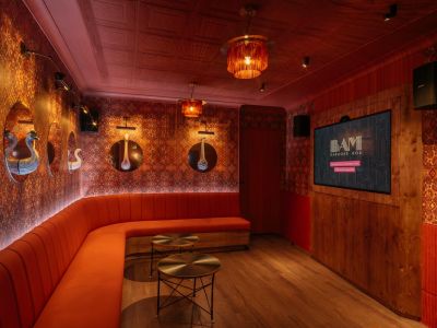 Red karaoke bar room with seating and screen.