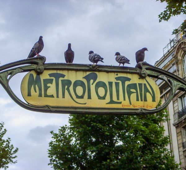 Paris metro sign with pigeons on it.