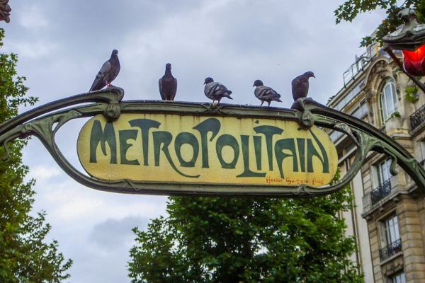 Paris metro sign with pigeons on it.