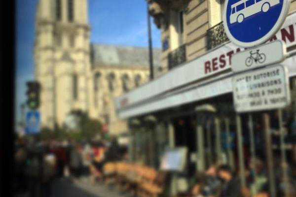 Paris bus stop sign with Notre Dame in the background.